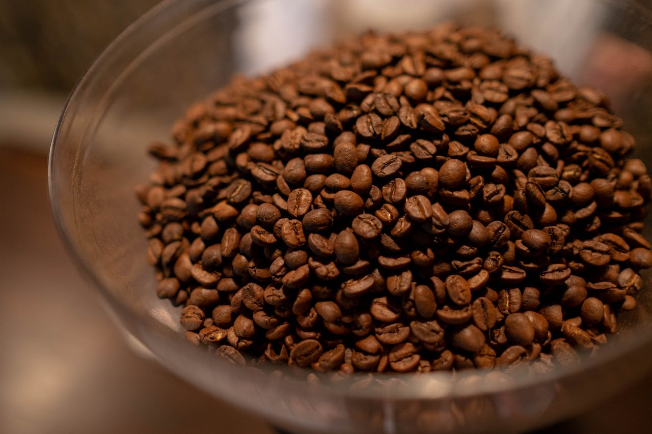 A rich, detailed close-up of aromatic roasted coffee beans in a glass bowl, perfect for caffeine lovers.